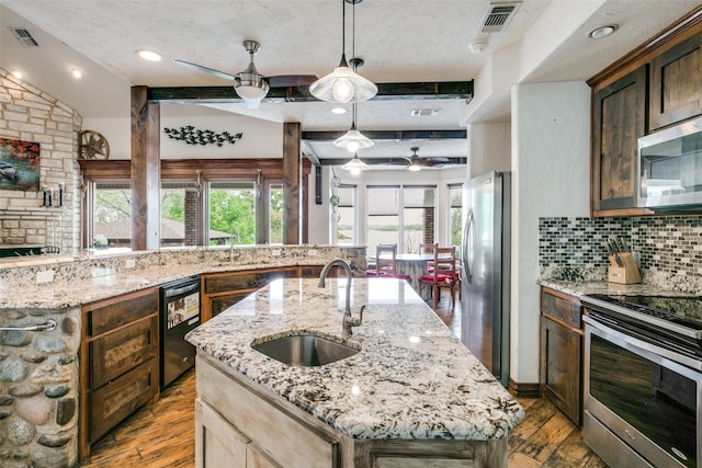 kitchen with stainless steel appliances, ceiling fan, a center island with sink, lofted ceiling, and sink