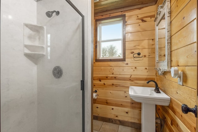 bathroom featuring wooden walls, walk in shower, tile floors, and sink