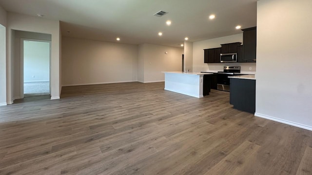 kitchen with stainless steel appliances, dark wood-type flooring, and a center island with sink