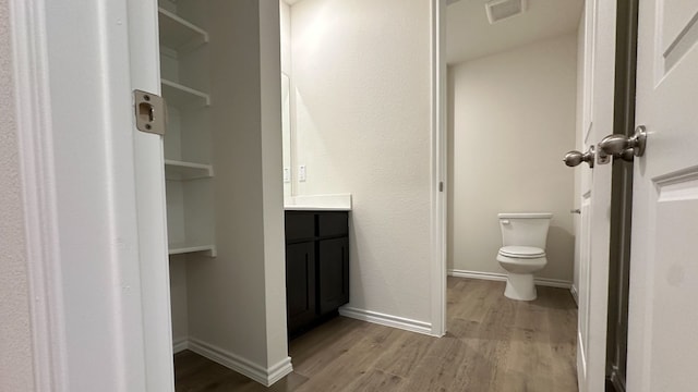 bathroom featuring wood-type flooring, toilet, and vanity