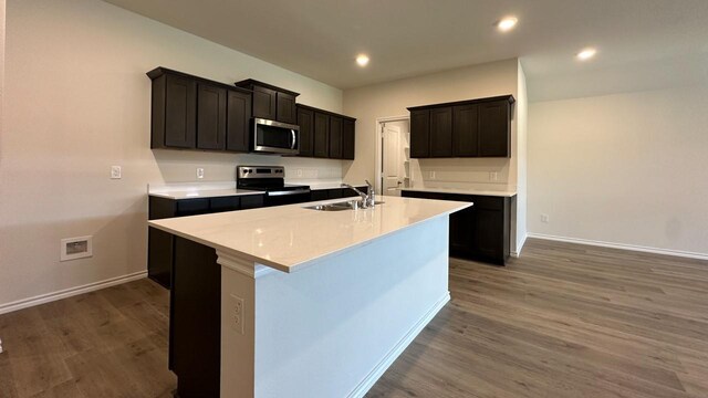 kitchen featuring a center island with sink, dark wood-type flooring, appliances with stainless steel finishes, and sink