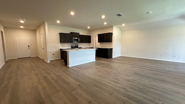 kitchen with sink, dark hardwood / wood-style floors, stainless steel appliances, and an island with sink