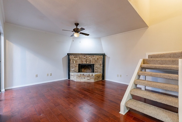 unfurnished living room with a fireplace, dark hardwood / wood-style flooring, ceiling fan, and crown molding