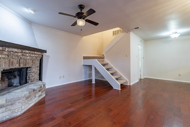 unfurnished living room with ceiling fan, a fireplace, dark wood-type flooring, and ornamental molding