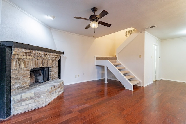 unfurnished living room with a brick fireplace, ceiling fan, dark hardwood / wood-style floors, and ornamental molding