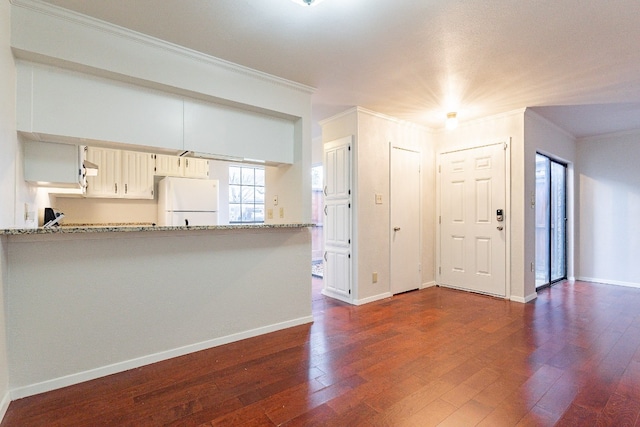 kitchen featuring kitchen peninsula, light stone countertops, crown molding, and white refrigerator