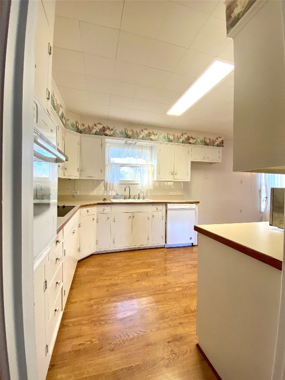 kitchen featuring light hardwood / wood-style floors, dishwasher, white cabinetry, and sink