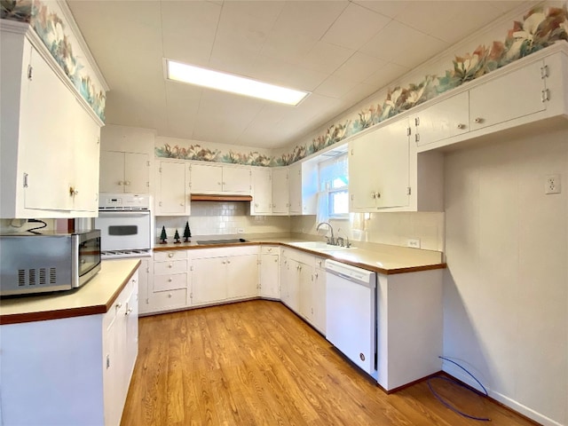 kitchen with white cabinets, sink, white appliances, and light hardwood / wood-style flooring