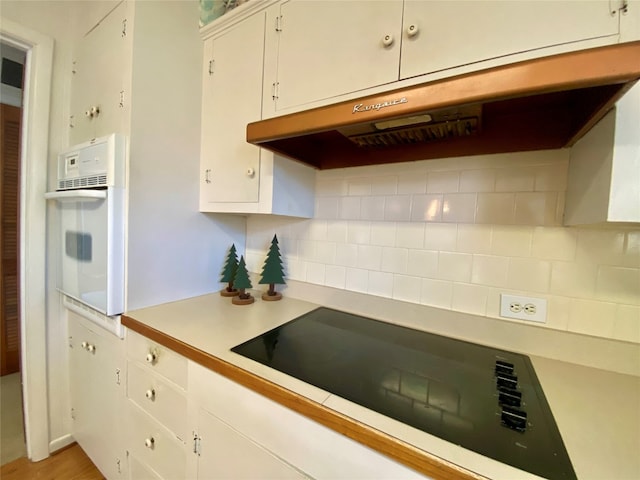 kitchen featuring backsplash, white oven, light hardwood / wood-style floors, and white cabinetry