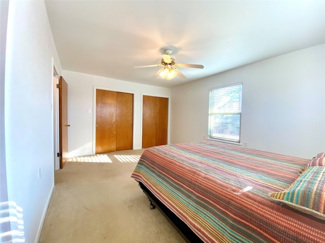 bedroom featuring multiple closets, ceiling fan, and light carpet