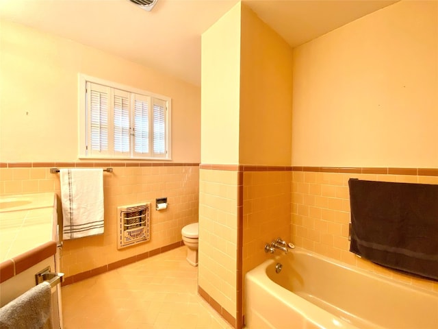 bathroom featuring a bathtub, tile floors, vanity, tile walls, and toilet