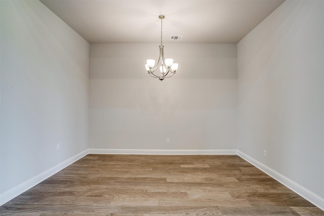 empty room featuring a chandelier and hardwood / wood-style flooring