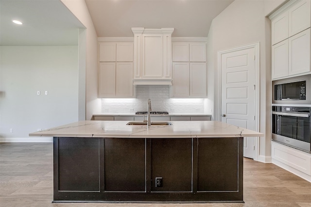 kitchen with an island with sink, light hardwood / wood-style floors, white cabinetry, and stainless steel appliances