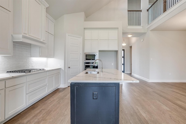 kitchen featuring light hardwood / wood-style floors, a kitchen island with sink, stainless steel appliances, and white cabinets