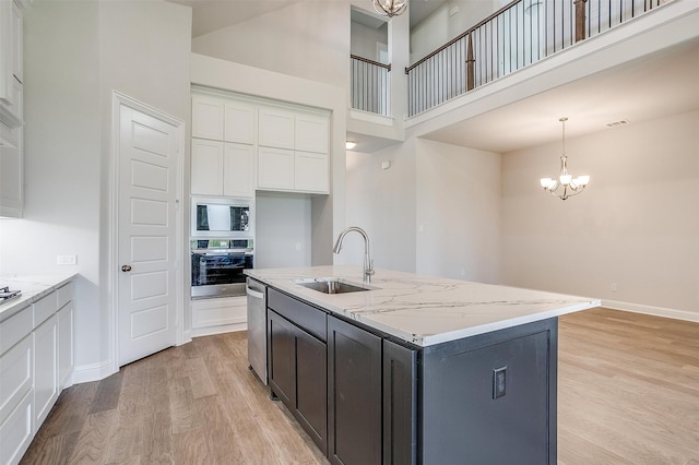 kitchen featuring appliances with stainless steel finishes, hanging light fixtures, white cabinetry, a kitchen island with sink, and sink