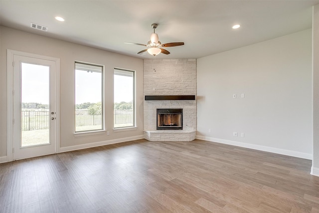 unfurnished living room featuring ceiling fan, a fireplace, and light hardwood / wood-style floors