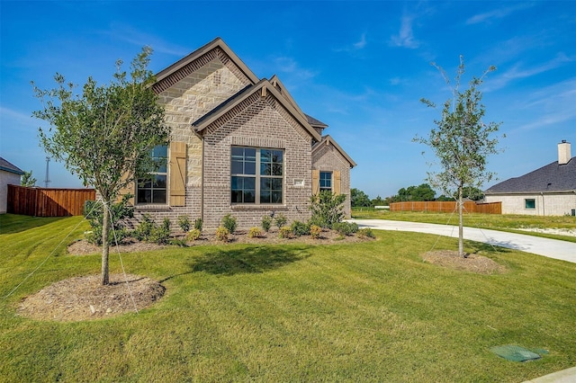 view of front of property with stone siding, brick siding, a front yard, and fence