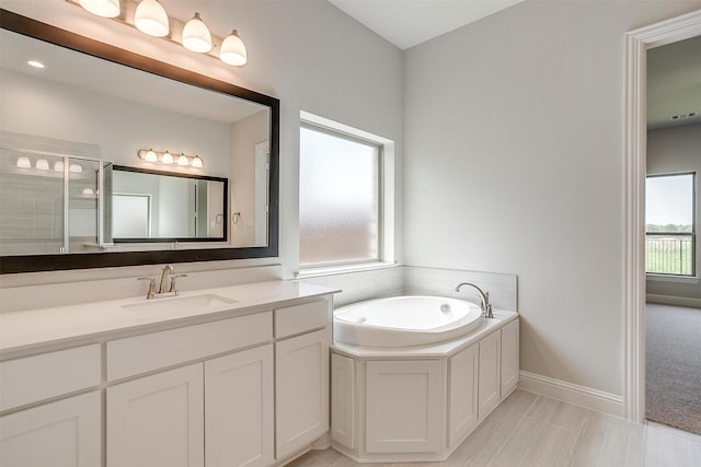 bathroom featuring a garden tub, a shower stall, baseboards, and vanity