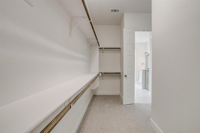 walk in closet with visible vents and light colored carpet