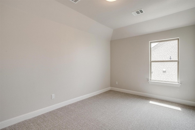 carpeted empty room with lofted ceiling, visible vents, and baseboards