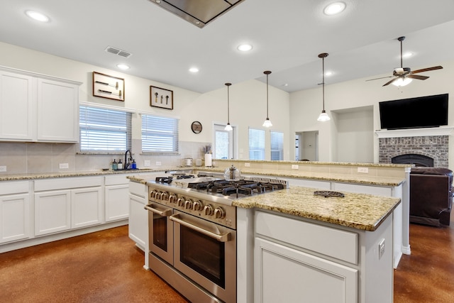 kitchen featuring a fireplace, concrete floors, range with two ovens, decorative light fixtures, and ceiling fan