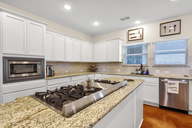 kitchen featuring appliances with stainless steel finishes, light stone counters, and white cabinetry