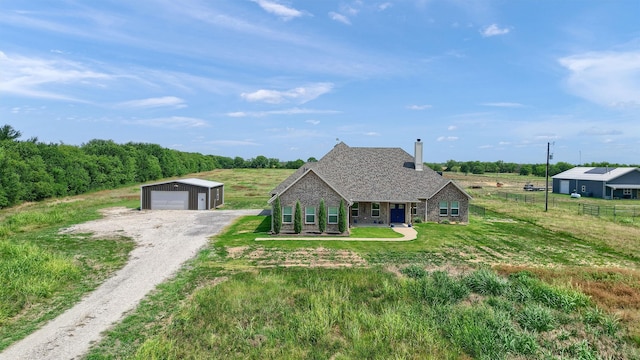 view of front of home with a rural view, an outbuilding, a garage, a front yard, and a porch