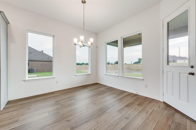 unfurnished dining area with a notable chandelier and light wood-type flooring