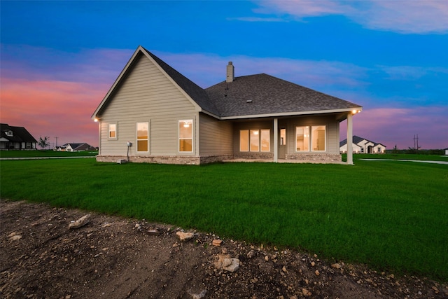 back house at dusk with a lawn