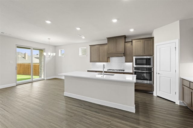 kitchen with stainless steel appliances, sink, an island with sink, and dark hardwood / wood-style flooring