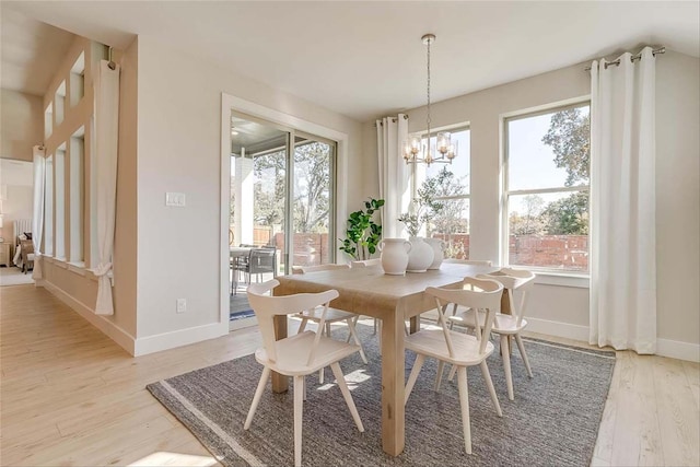 dining space with light hardwood / wood-style flooring and a notable chandelier