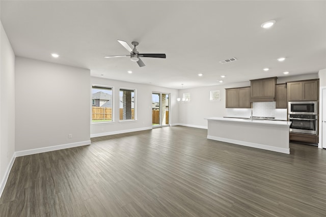 unfurnished living room featuring sink, ceiling fan with notable chandelier, and dark hardwood / wood-style flooring