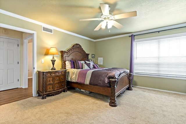 bedroom featuring ornamental molding, light colored carpet, and ceiling fan