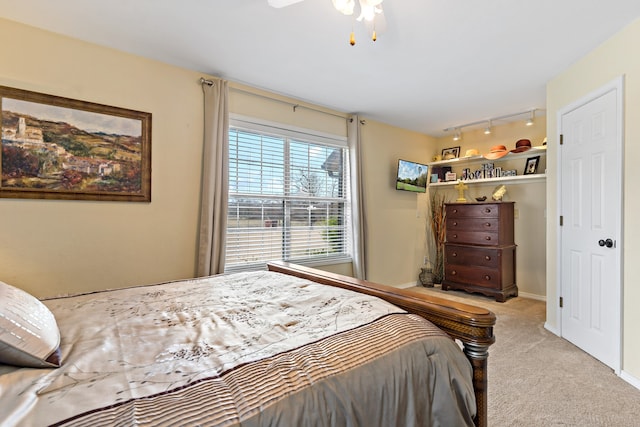 carpeted bedroom with track lighting and ceiling fan