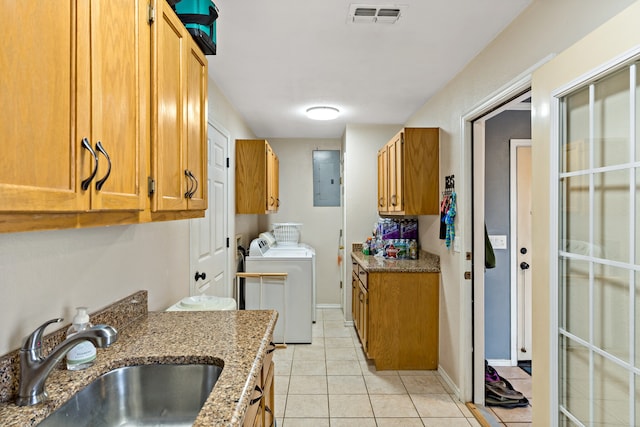 kitchen featuring sink, light tile patterned floors, light stone countertops, washer and dryer, and electric panel