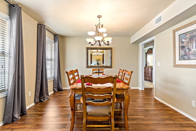 dining area with dark wood-type flooring and a chandelier