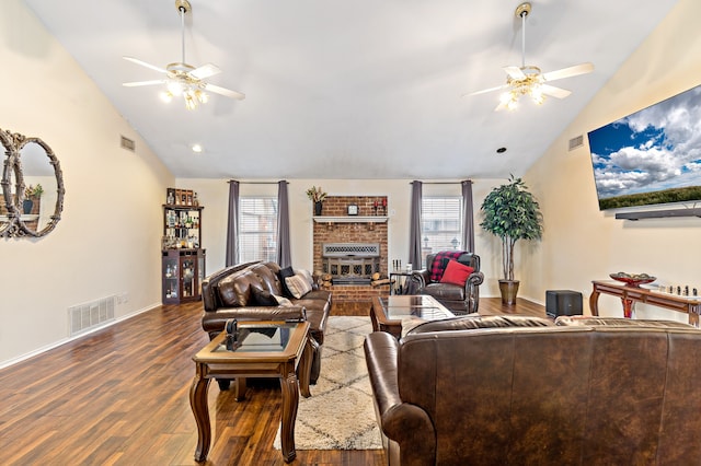 living room featuring ceiling fan, dark wood-type flooring, a brick fireplace, and plenty of natural light