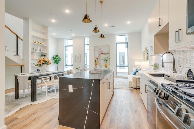 kitchen featuring light hardwood / wood-style flooring, decorative light fixtures, stainless steel appliances, a kitchen island, and tasteful backsplash