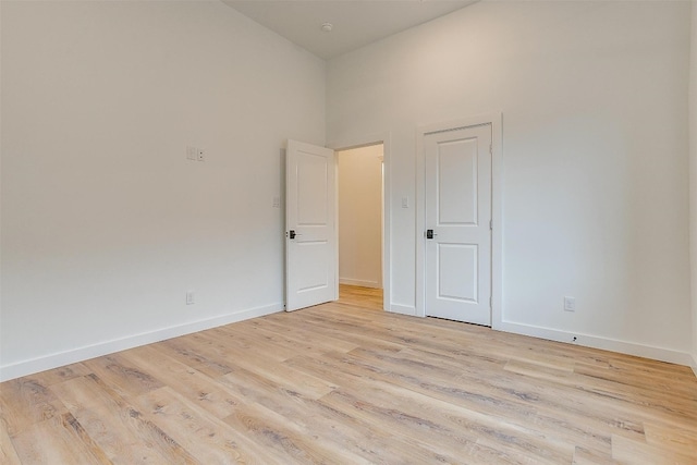 spare room with light hardwood / wood-style floors and a towering ceiling