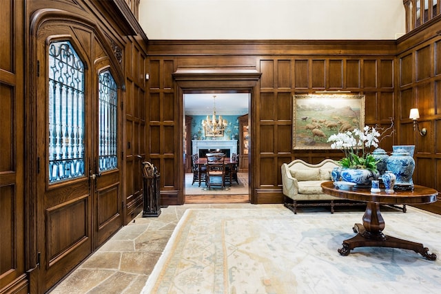 entryway featuring wooden walls, ornamental molding, and a notable chandelier