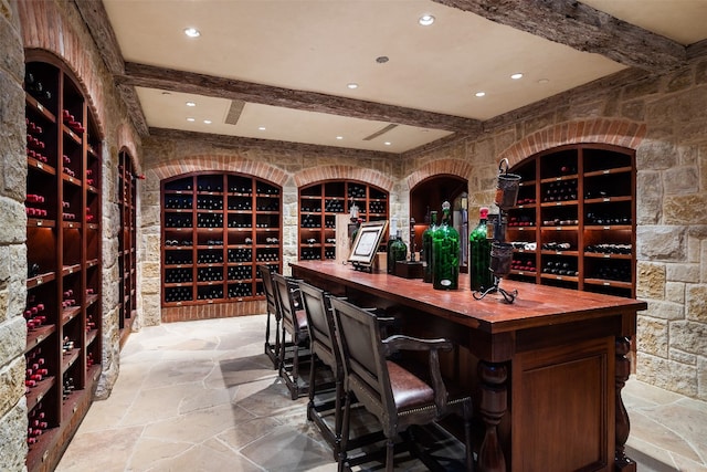 wine room with bar, beam ceiling, and light tile floors