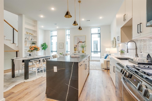 kitchen featuring white cabinets, a center island, light wood-type flooring, stainless steel appliances, and decorative backsplash