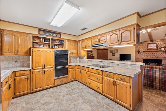 kitchen featuring under cabinet range hood, open shelves, a peninsula, light countertops, and black appliances