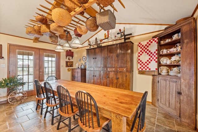 dining area with lofted ceiling, french doors, and stone tile flooring