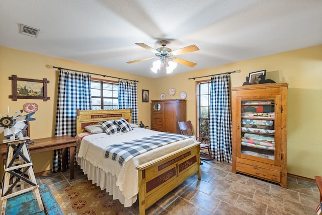 bedroom with stone finish flooring, multiple windows, and visible vents