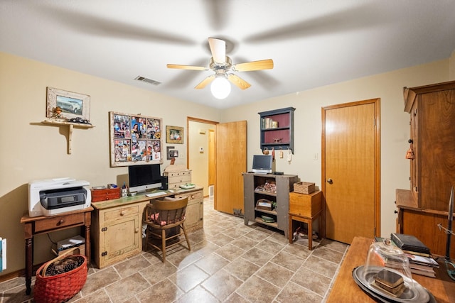 home office with ceiling fan, stone finish flooring, and visible vents