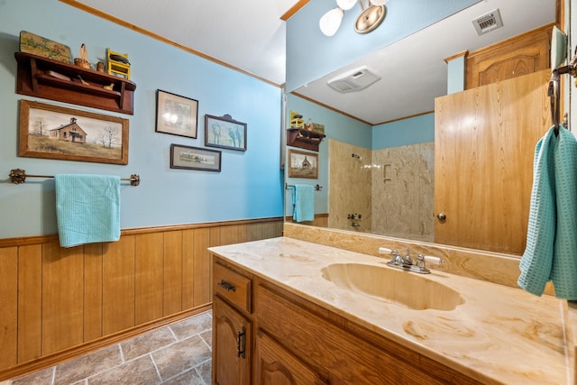 full bathroom featuring a wainscoted wall, visible vents, walk in shower, and crown molding