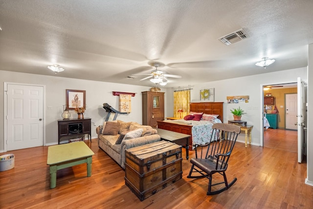 bedroom featuring visible vents, a ceiling fan, a textured ceiling, wood finished floors, and baseboards