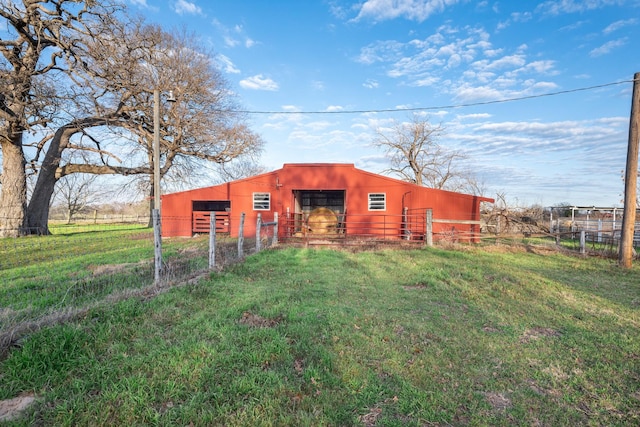 view of pole building featuring an exterior structure, a lawn, and fence