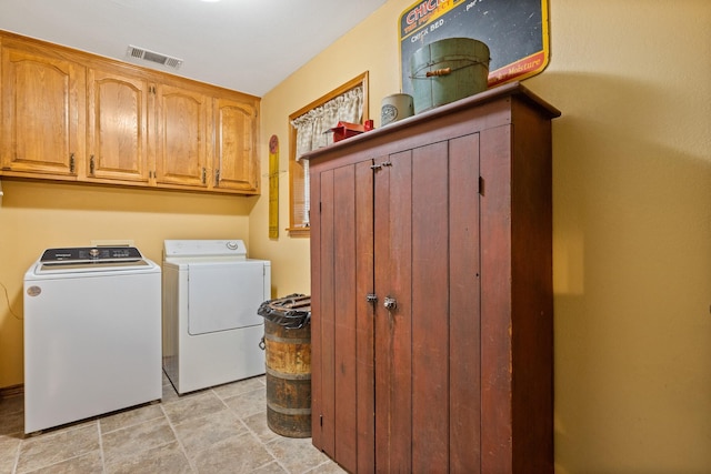 laundry area with visible vents, washing machine and clothes dryer, and cabinet space